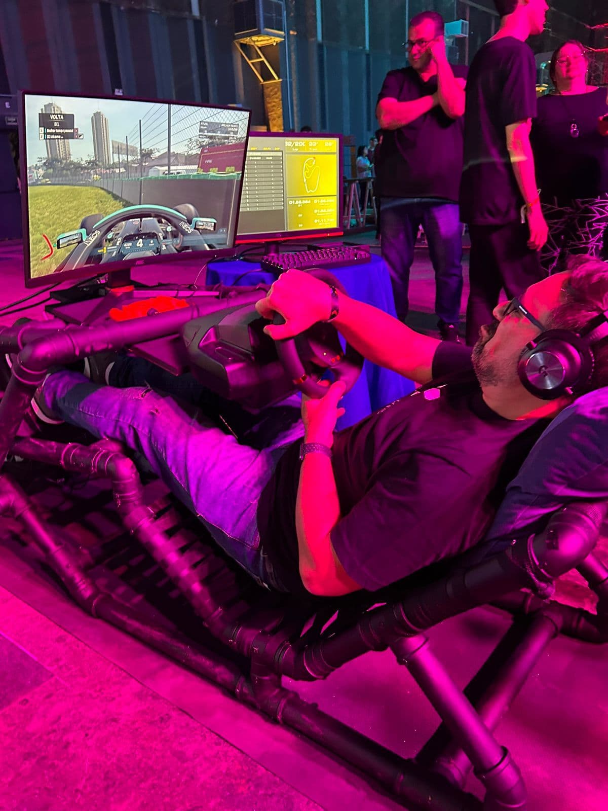 Driver reclined in the telemetry rig with the live dashboard on screen